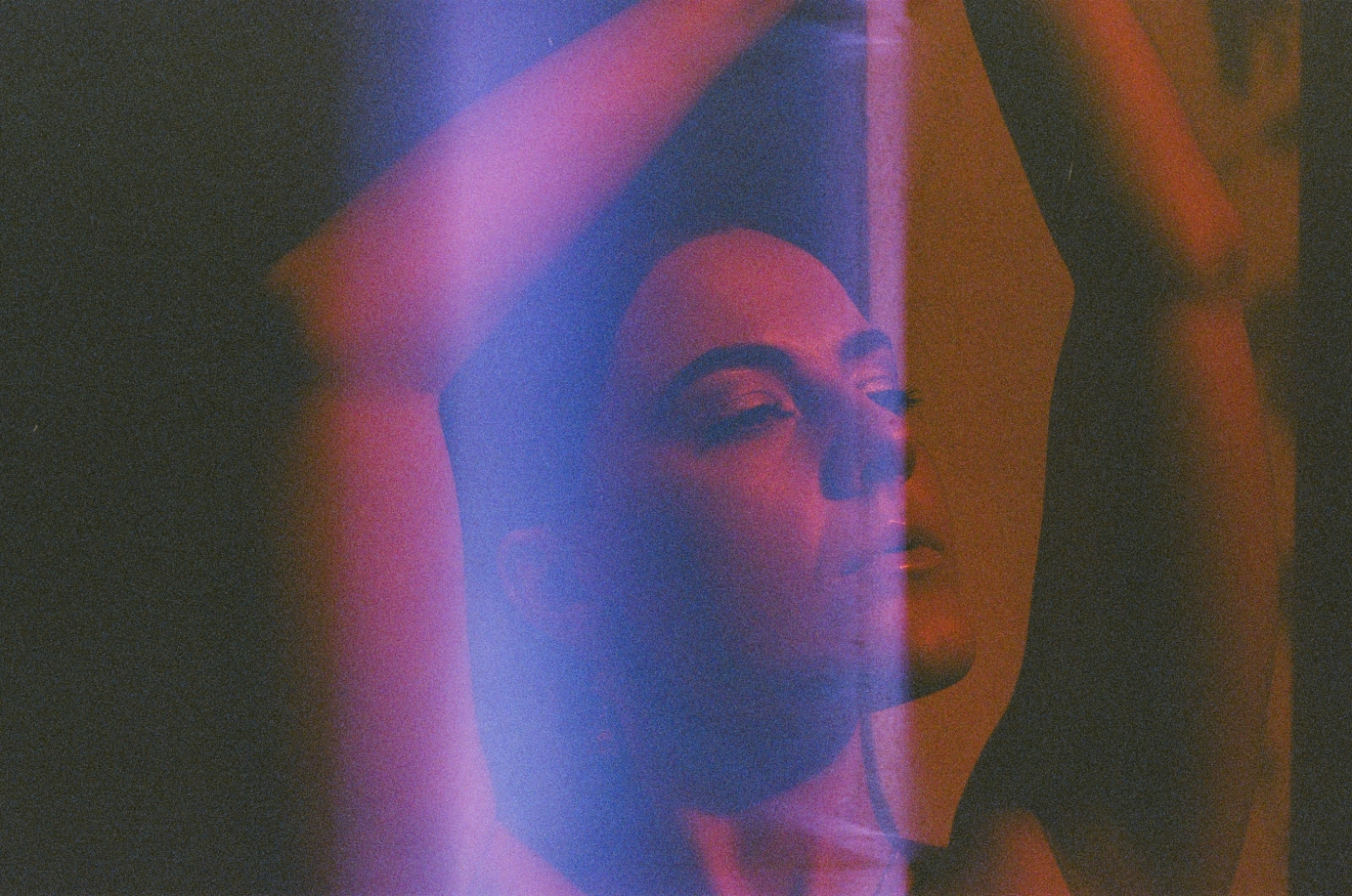 Analogue portrait of artist Liv East, shot on redscale 35mm film, with a light leak covering the middle of the portrait