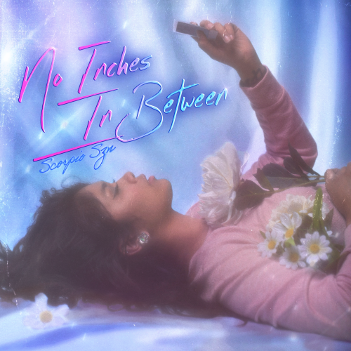 Image of Zandi Ashley of Scorpio Szn lying down on the ground with flowers around her, holding a polaroid.