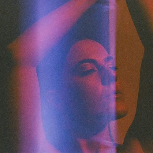 Analogue portrait of artist Liv East, shot on redscale 35mm film, with a light leak covering the middle of the portrait