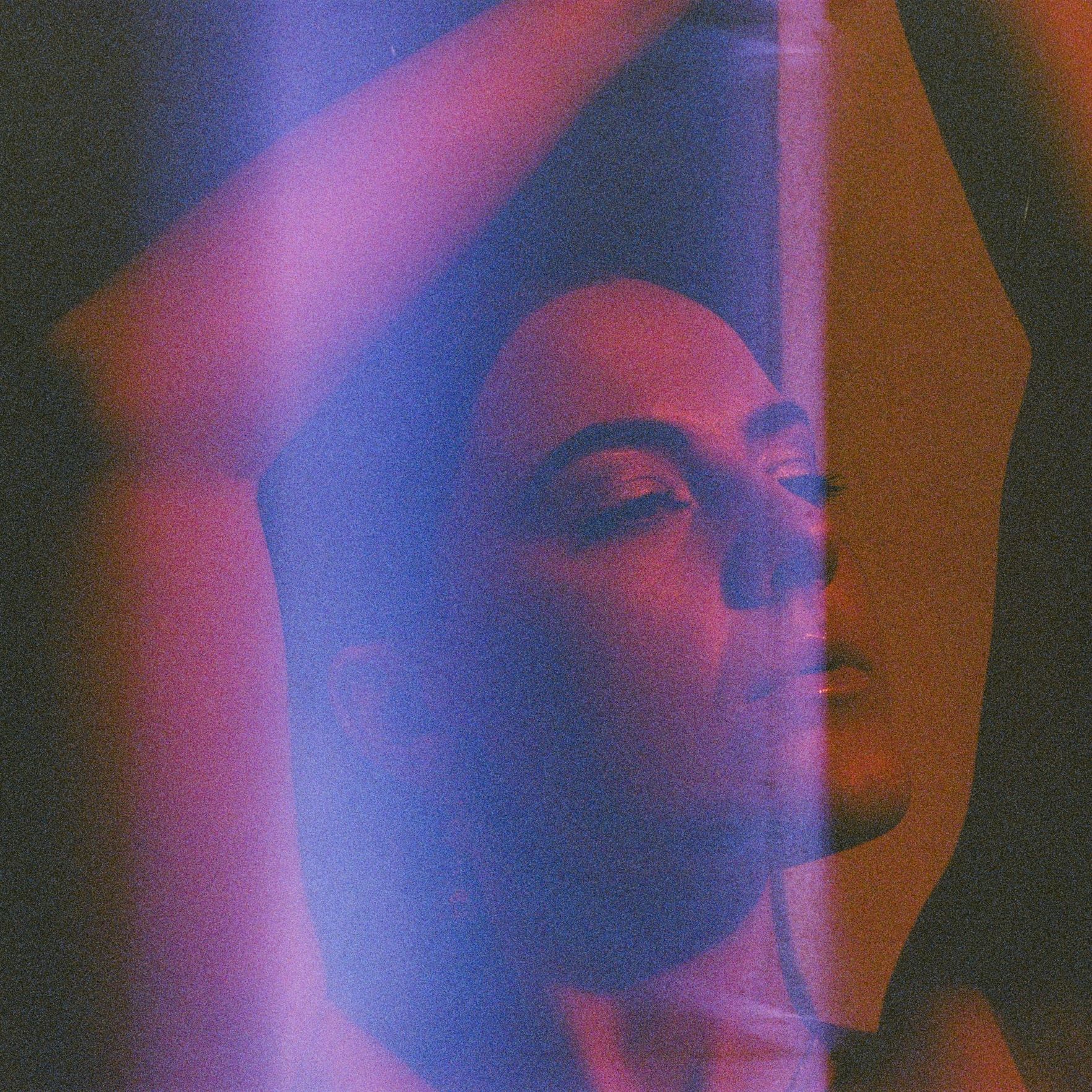 Analogue portrait of artist Liv East, shot on redscale 35mm film, with a light leak covering the middle of the portrait